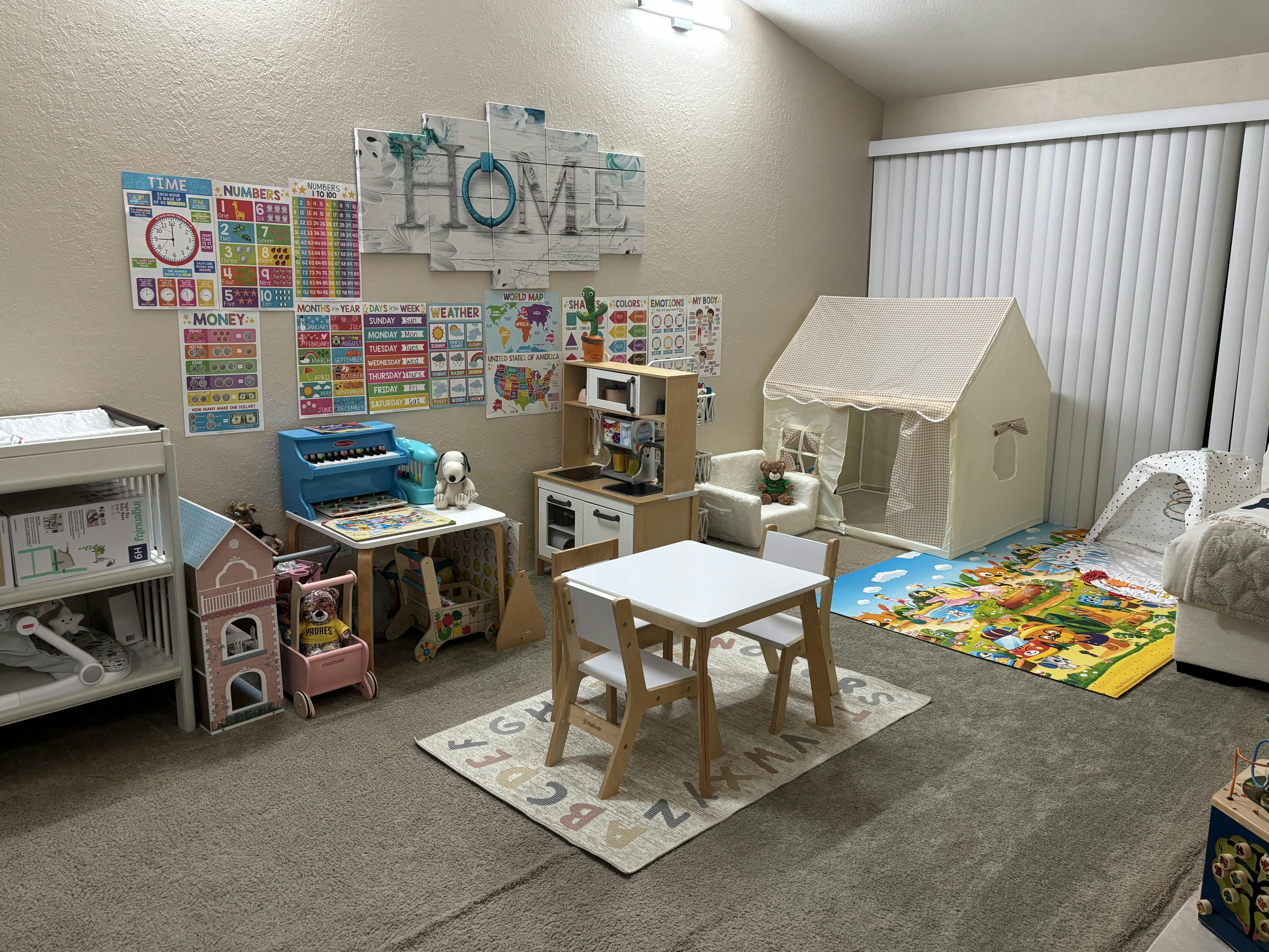 Children's play area with a kitchen, tent, table, and educational posters