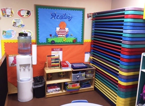 Classroom with a water cooler, shelves, and stacked colorful mats