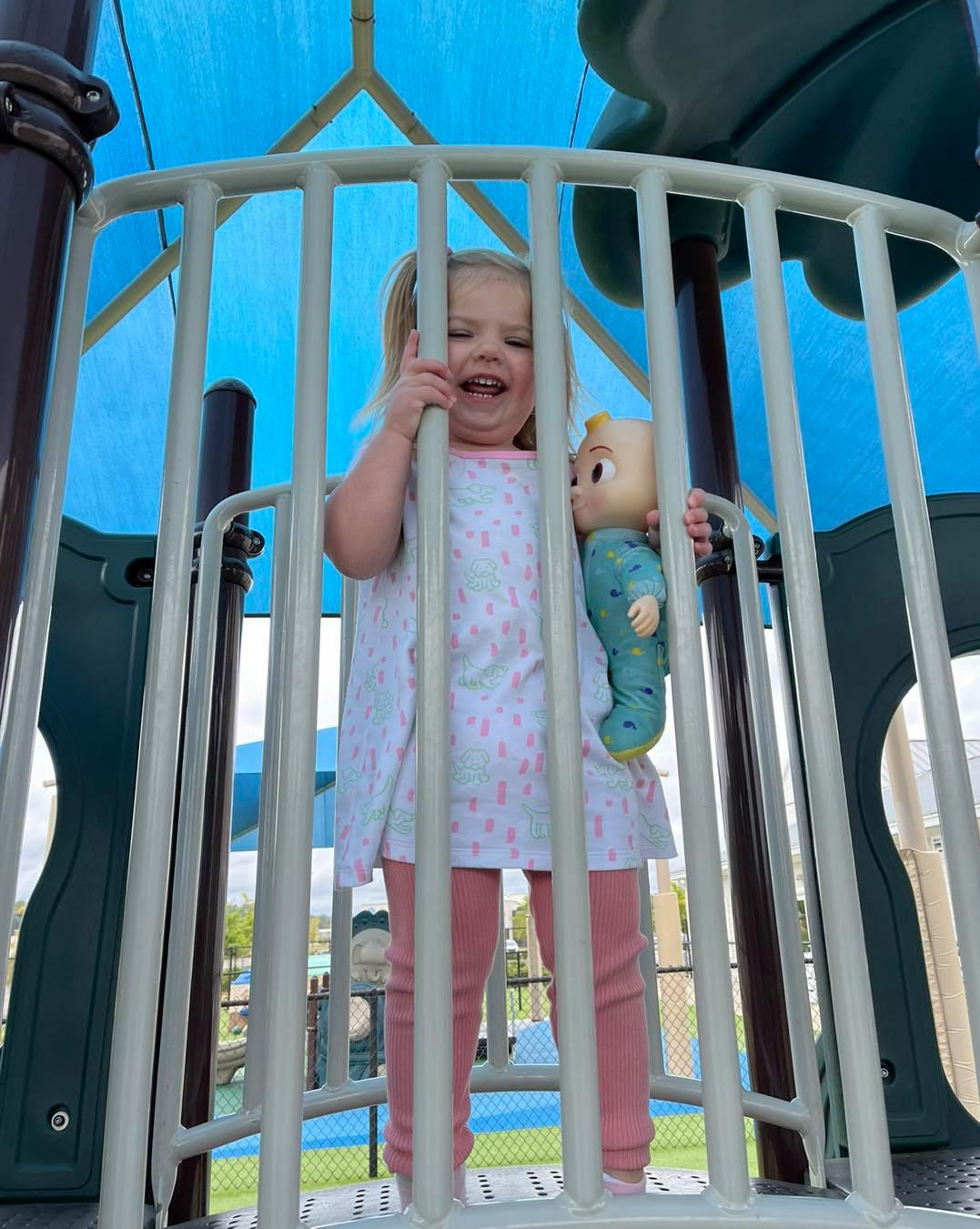 Child holding a doll on a playground structure