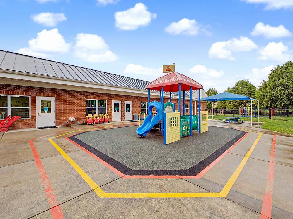 Playground with a small structure and slide next to a brick building