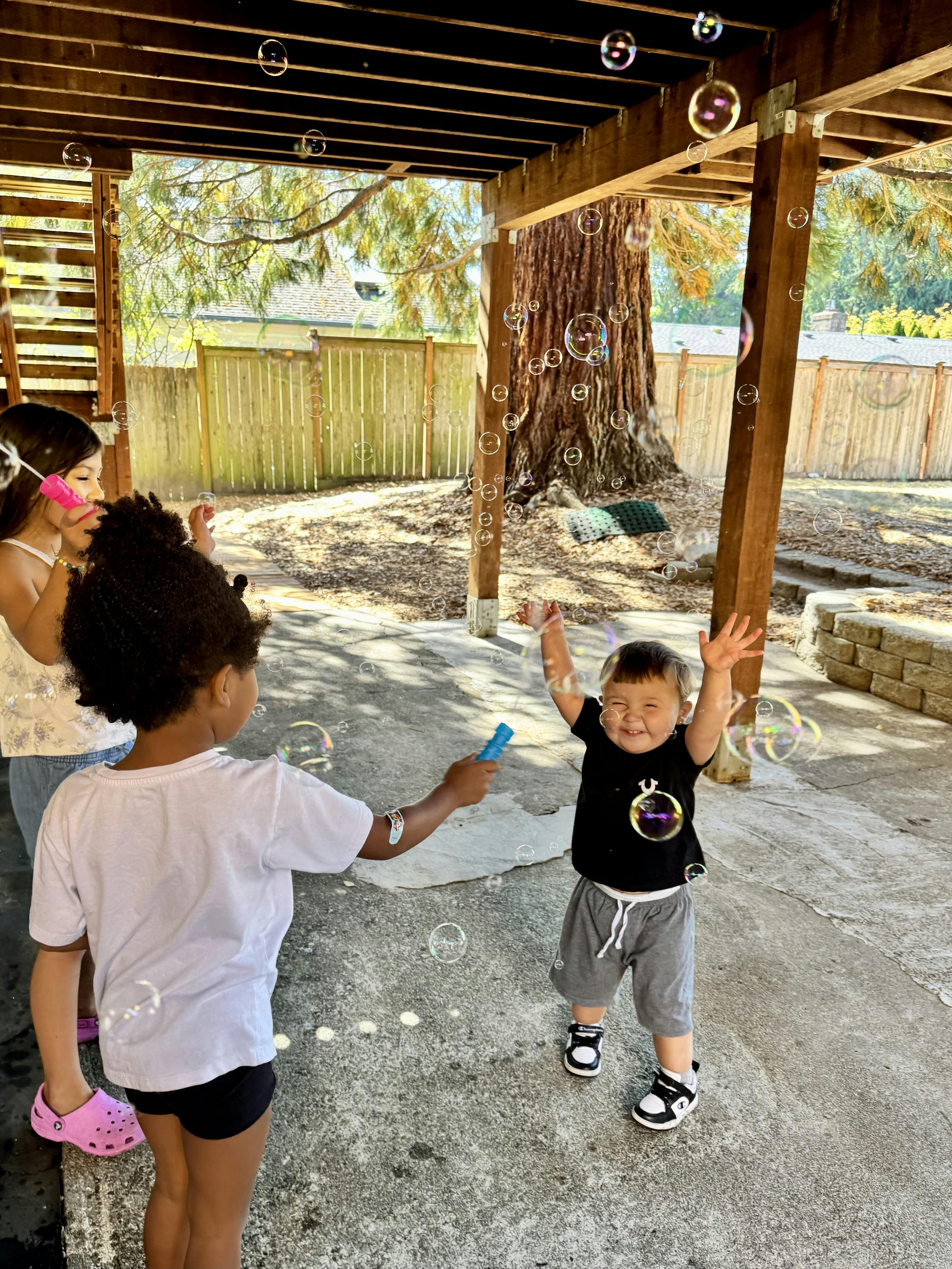 People blowing bubbles at a child in an outdoor space