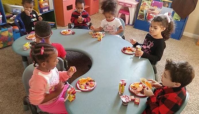 Children eating snacks at a table in a classroom