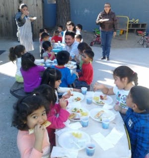 Adults and children eating at an outdoor table