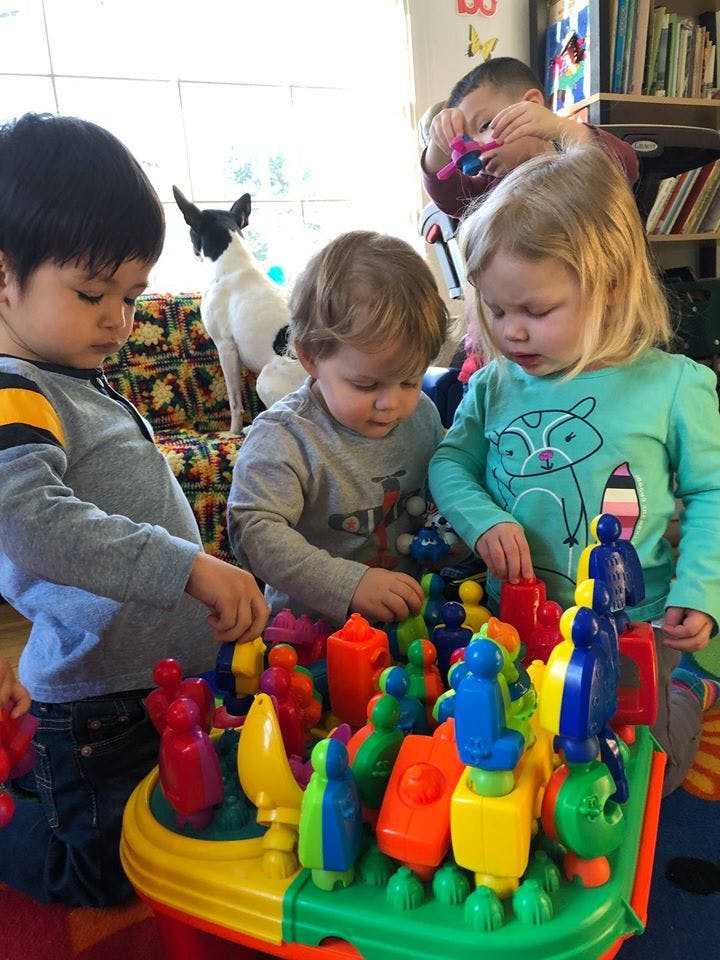 Three children playing with colorful building blocks