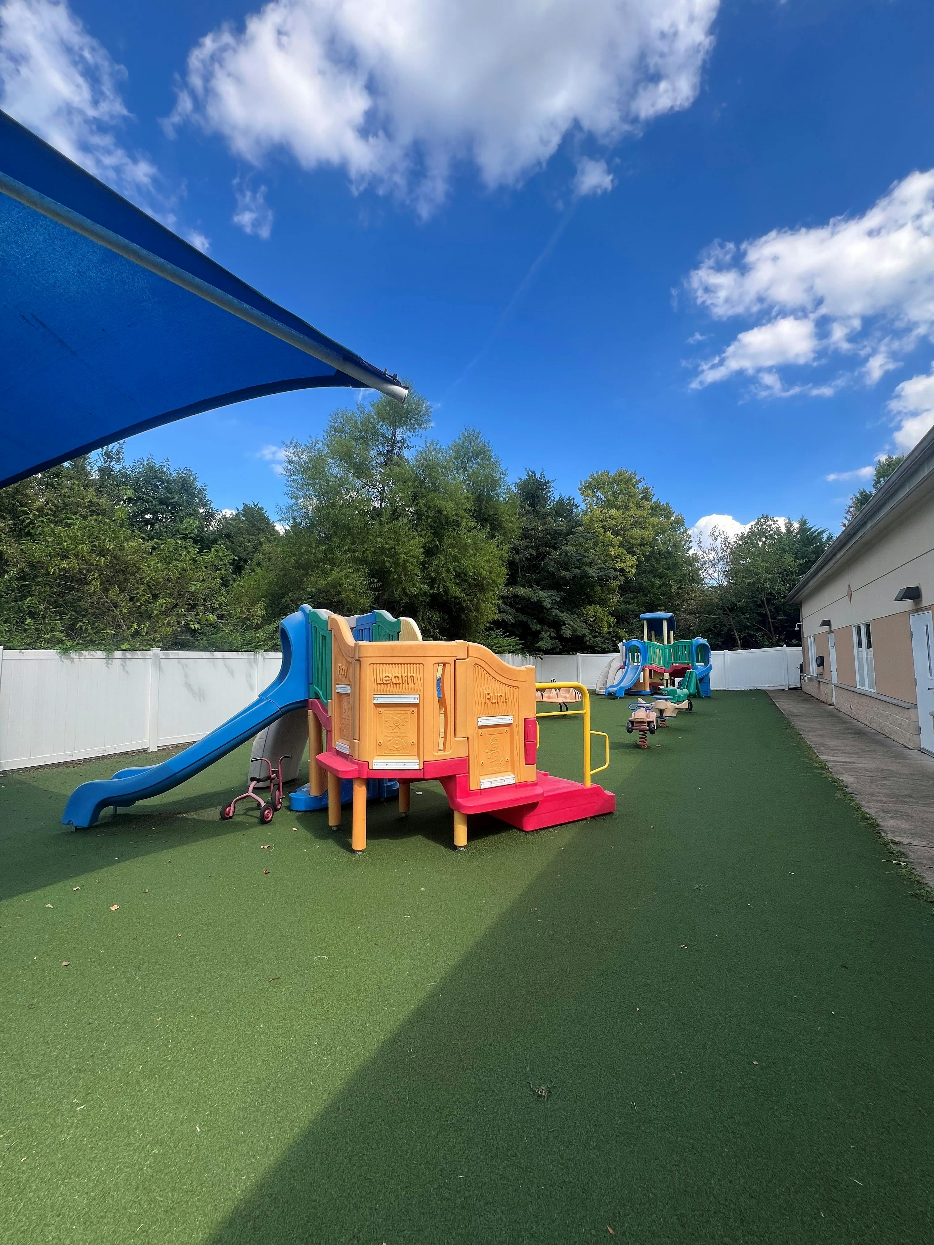 Playground equipment on a synthetic grass yard under a blue sky