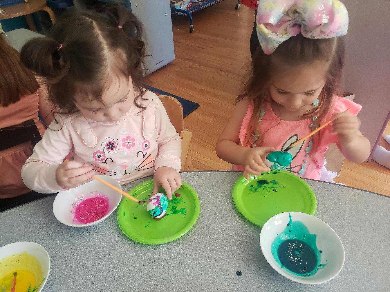 Two children painting eggs at a table