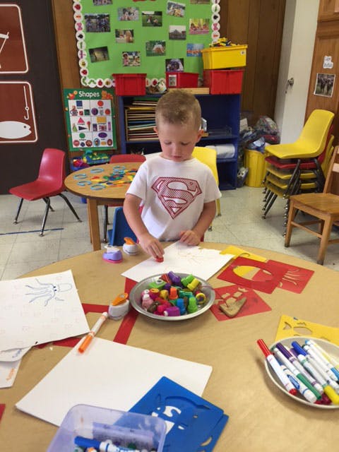Child in a classroom working on an art project at a table
