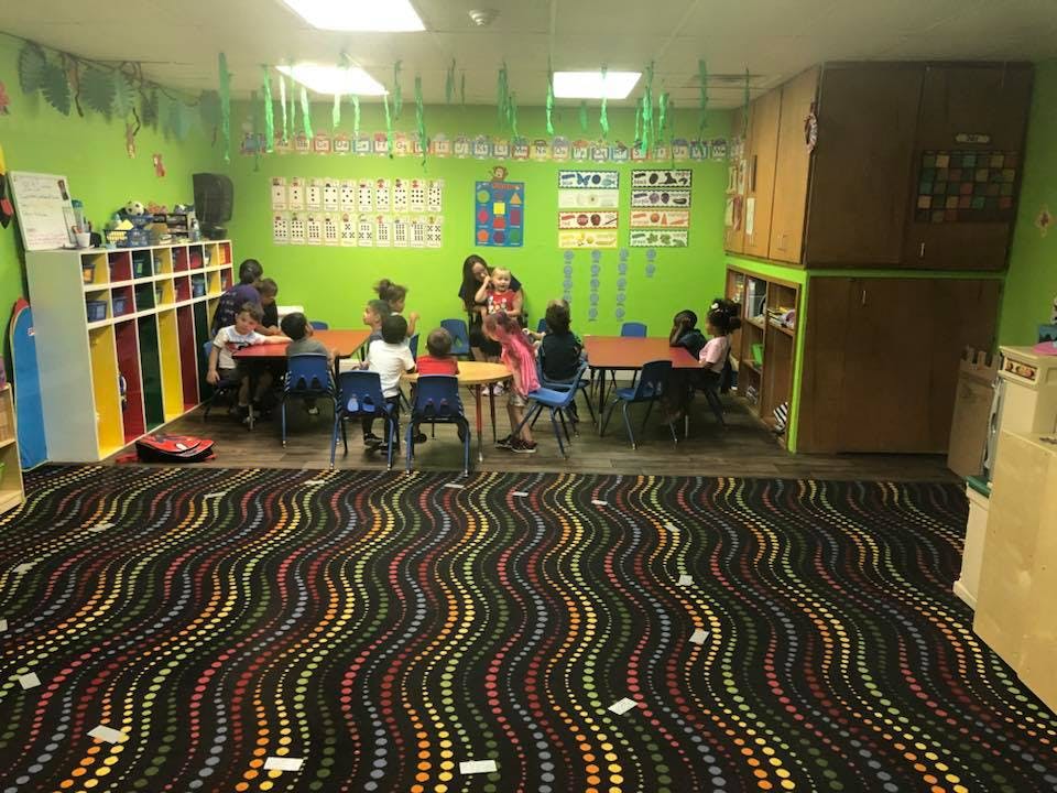 Children and adults sitting at tables in a classroom