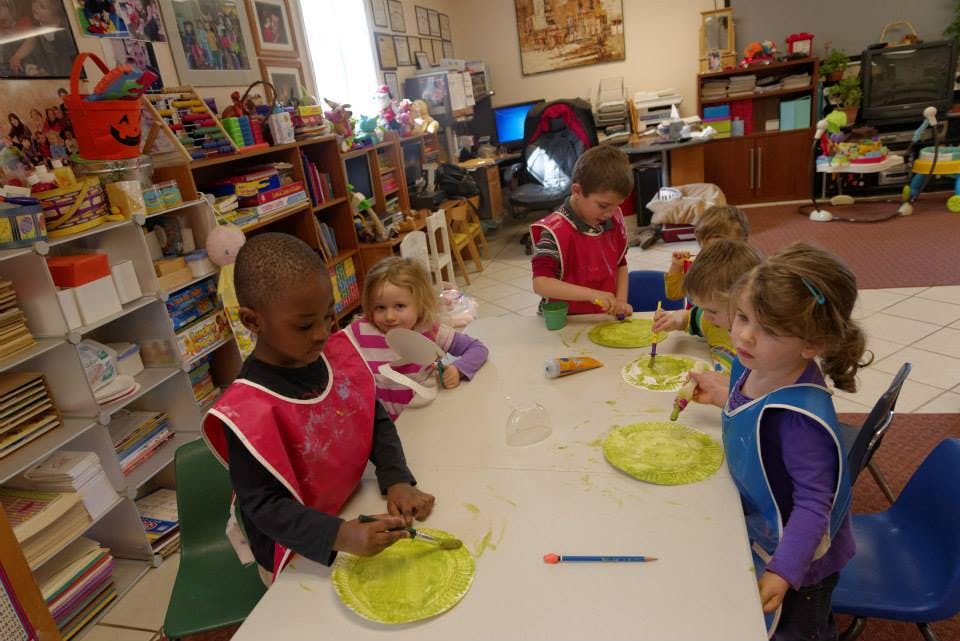 Children painting at a table in a classroom