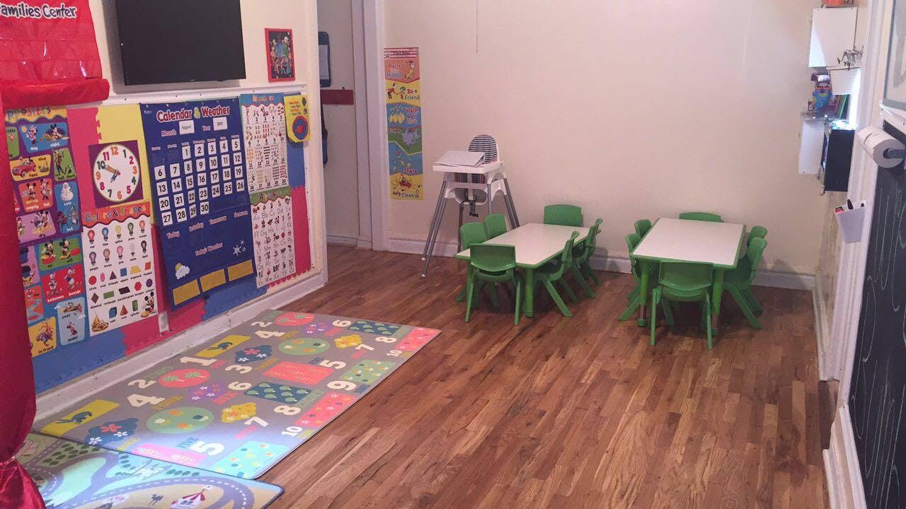 Classroom with small tables and chairs, colorful rug, and wall decorations