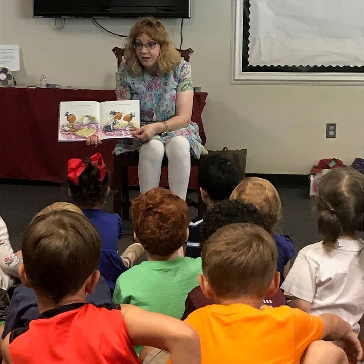Person reading a book to a group of children