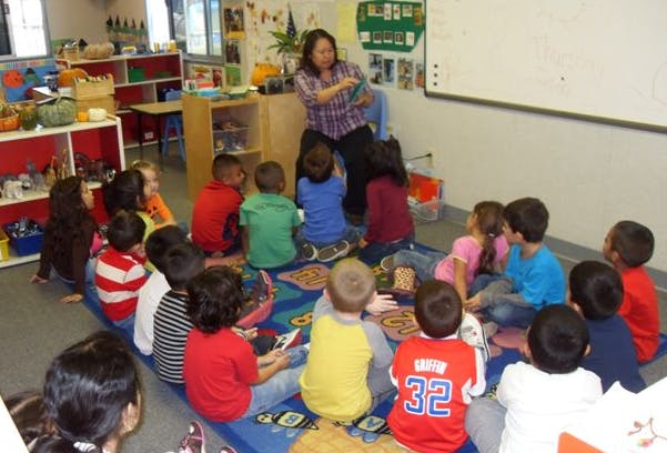 Adult and children sitting on a rug in a classroom