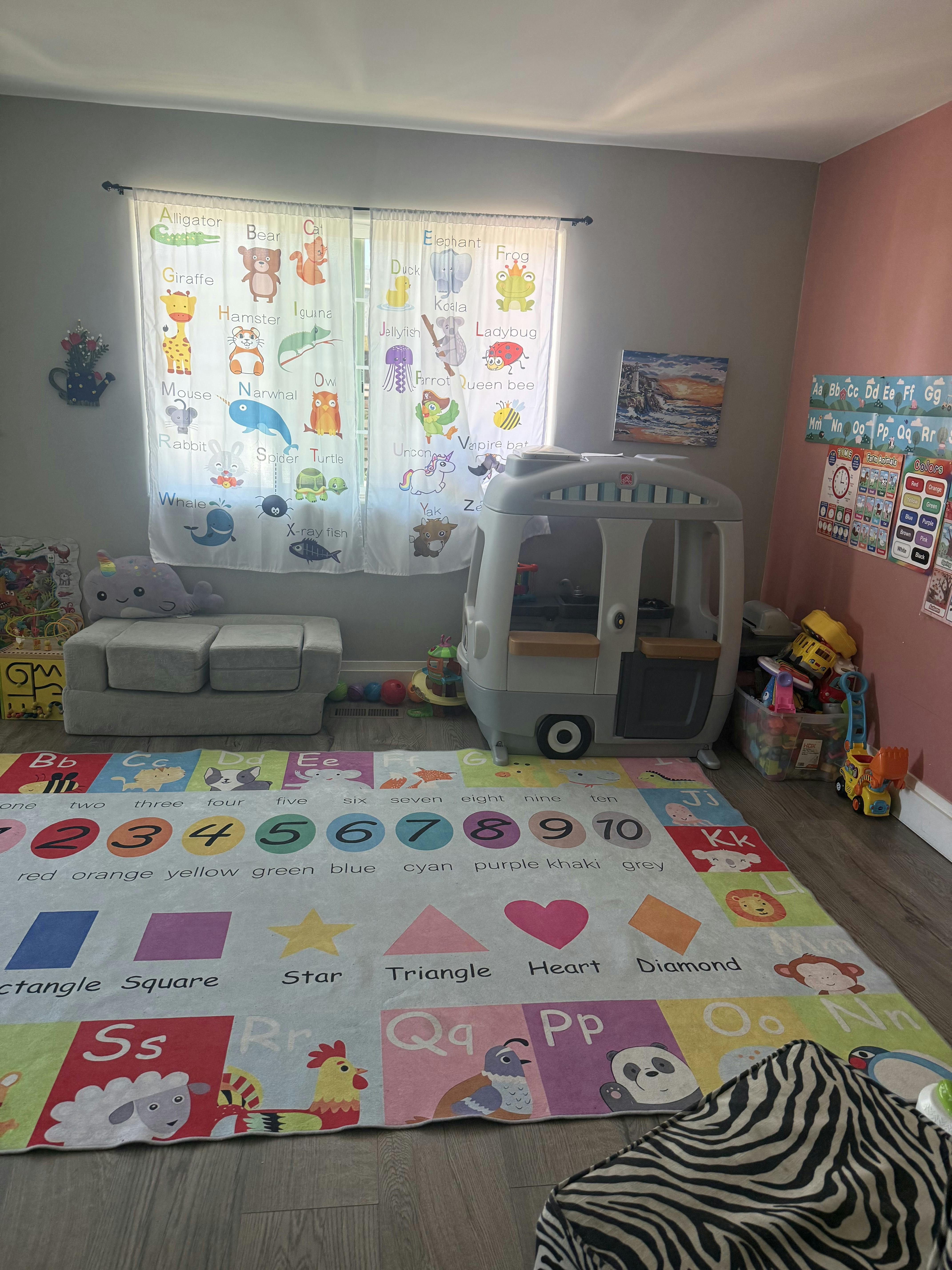 Playroom with alphabet curtains, a colorful learning rug, and toys