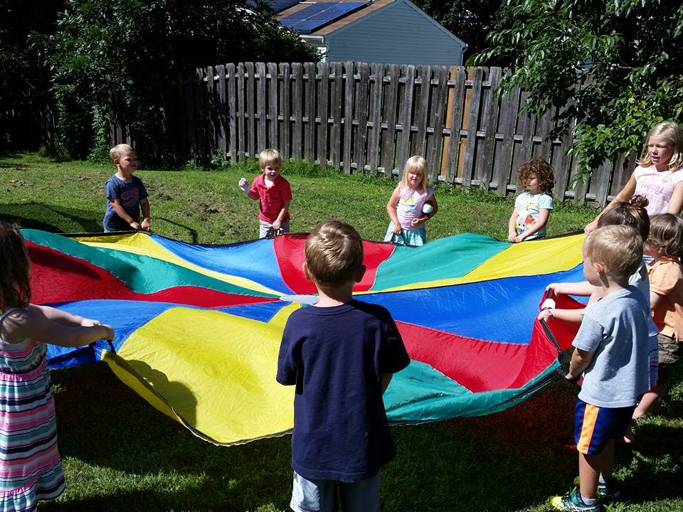 Children playing with a colorful parachute outdoors