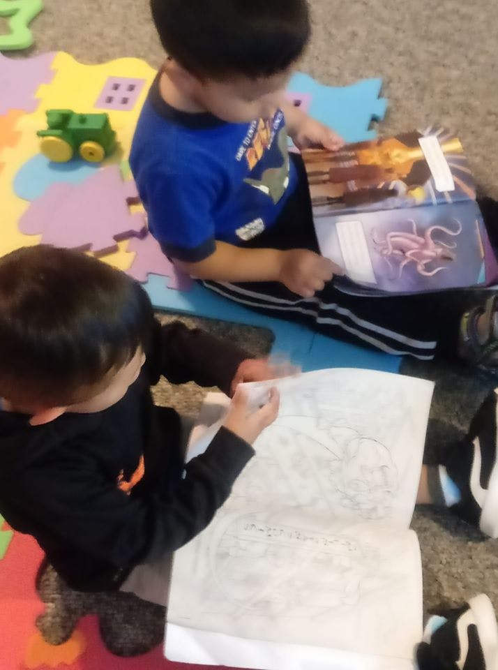 Two children sitting on the floor reading books