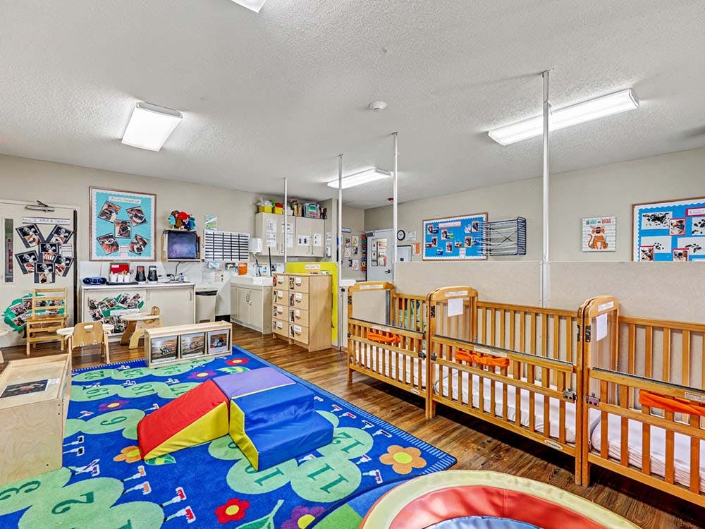 A colorful classroom with cribs and play equipment