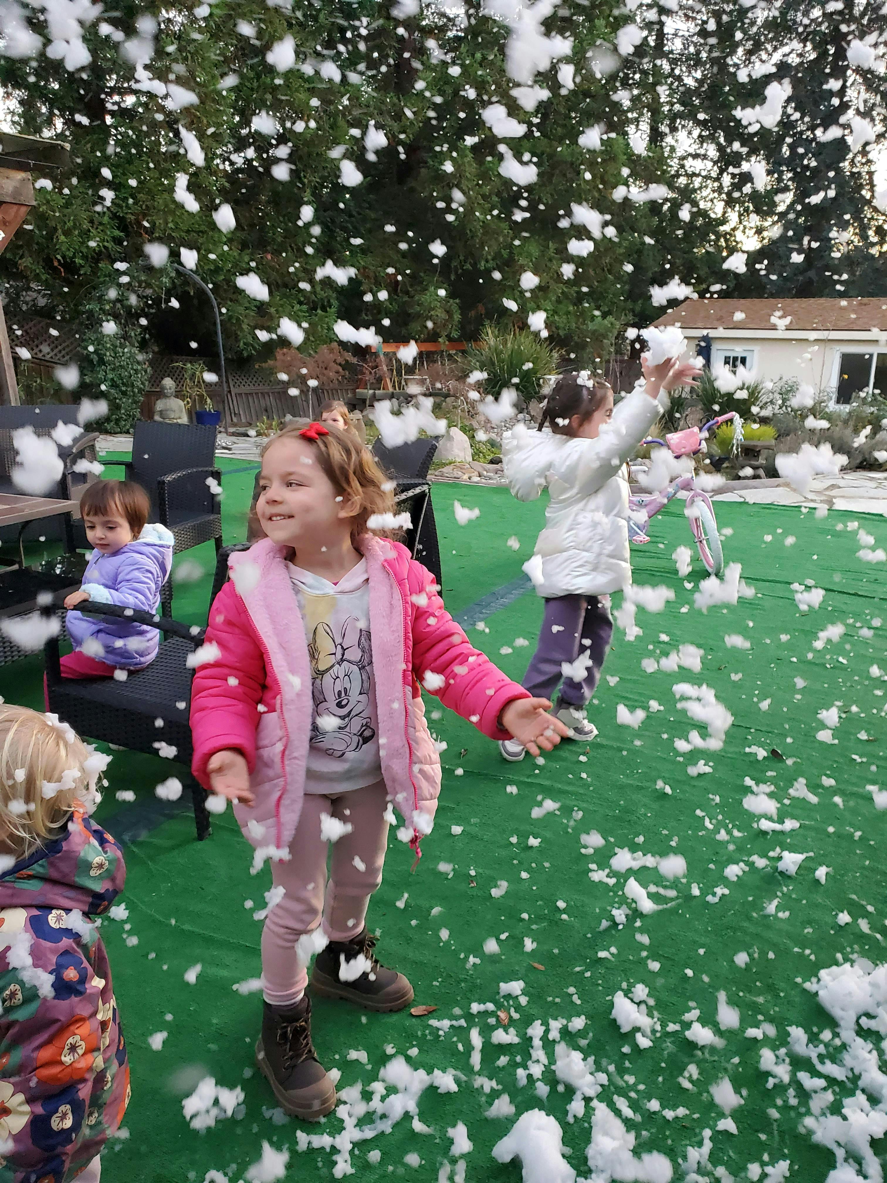 Children playing with falling white foam resembling snow