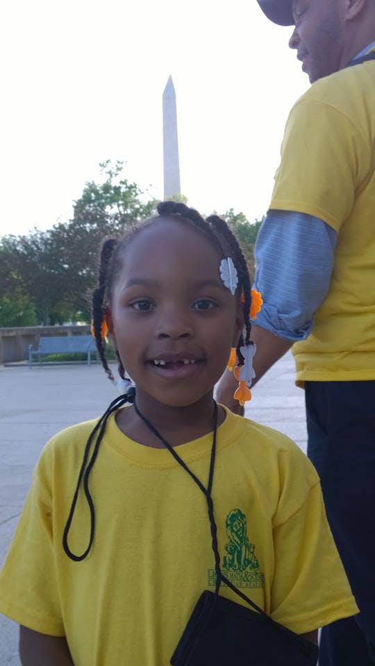 Child smiling with a missing front tooth, Washington Monument in background