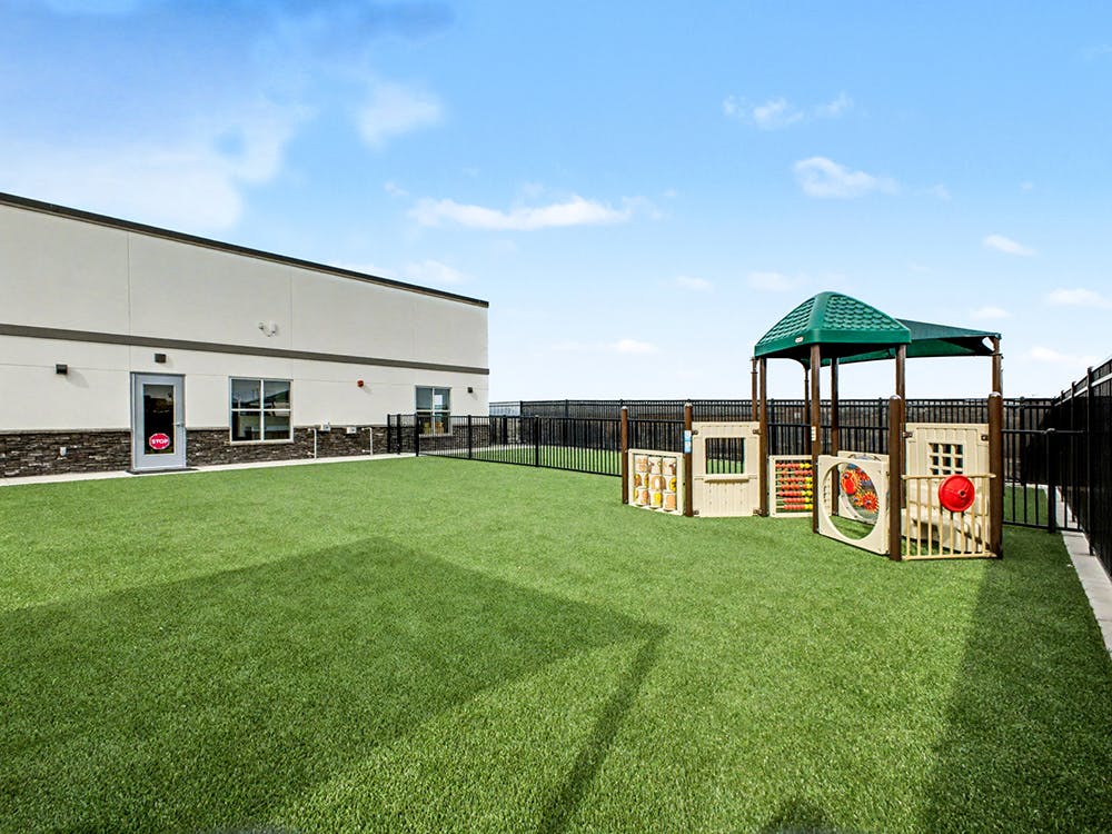 Fenced playground with artificial turf and play equipment