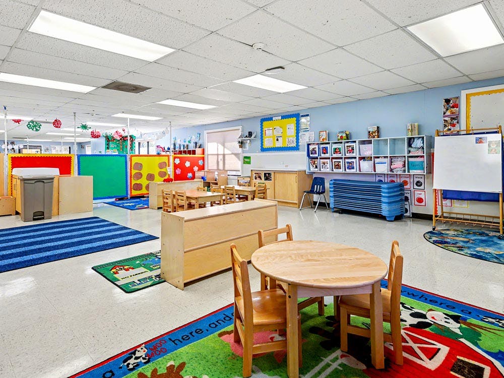 Empty colorful preschool classroom with small tables and chairs