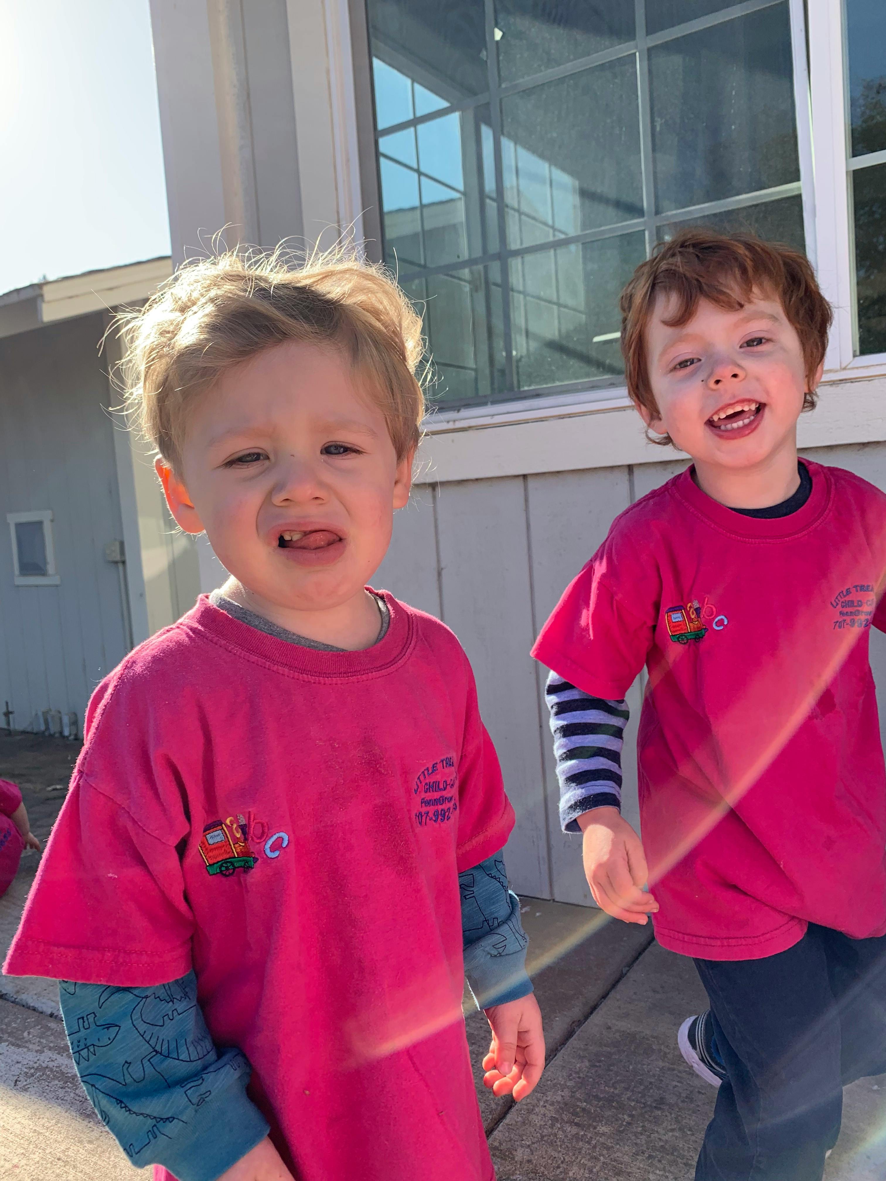 Two children in pink shirts standing outdoors