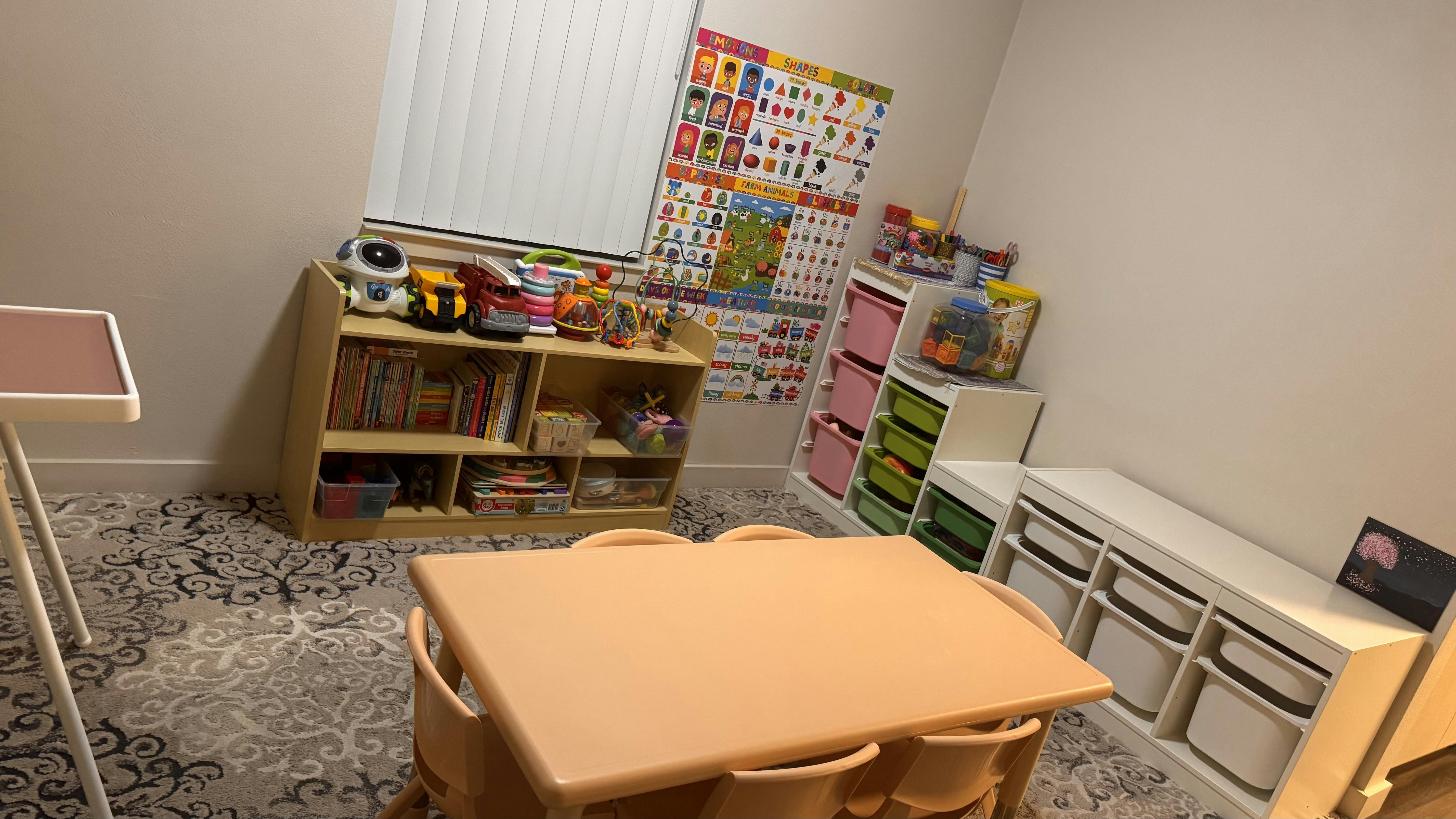 Children's play area with small table and chairs, shelves with toys and books