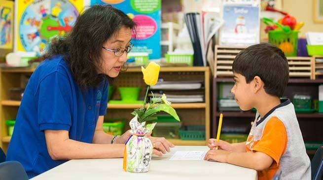 Person and child at a table in a classroom