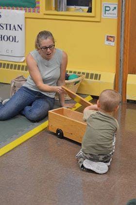 Person and child playing with a wooden toy truck
