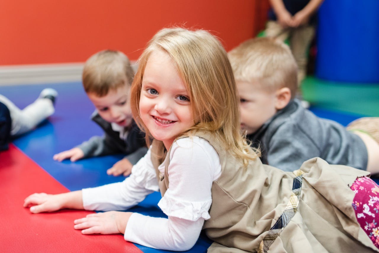 Child lying on stomach on a colorful mat with other children