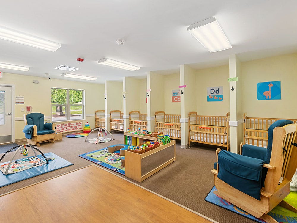 Baby room with multiple cribs, a rocking chair, and play mats