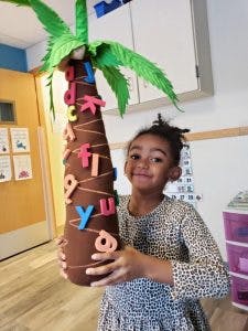 Child holding a craft palm tree with alphabet letters