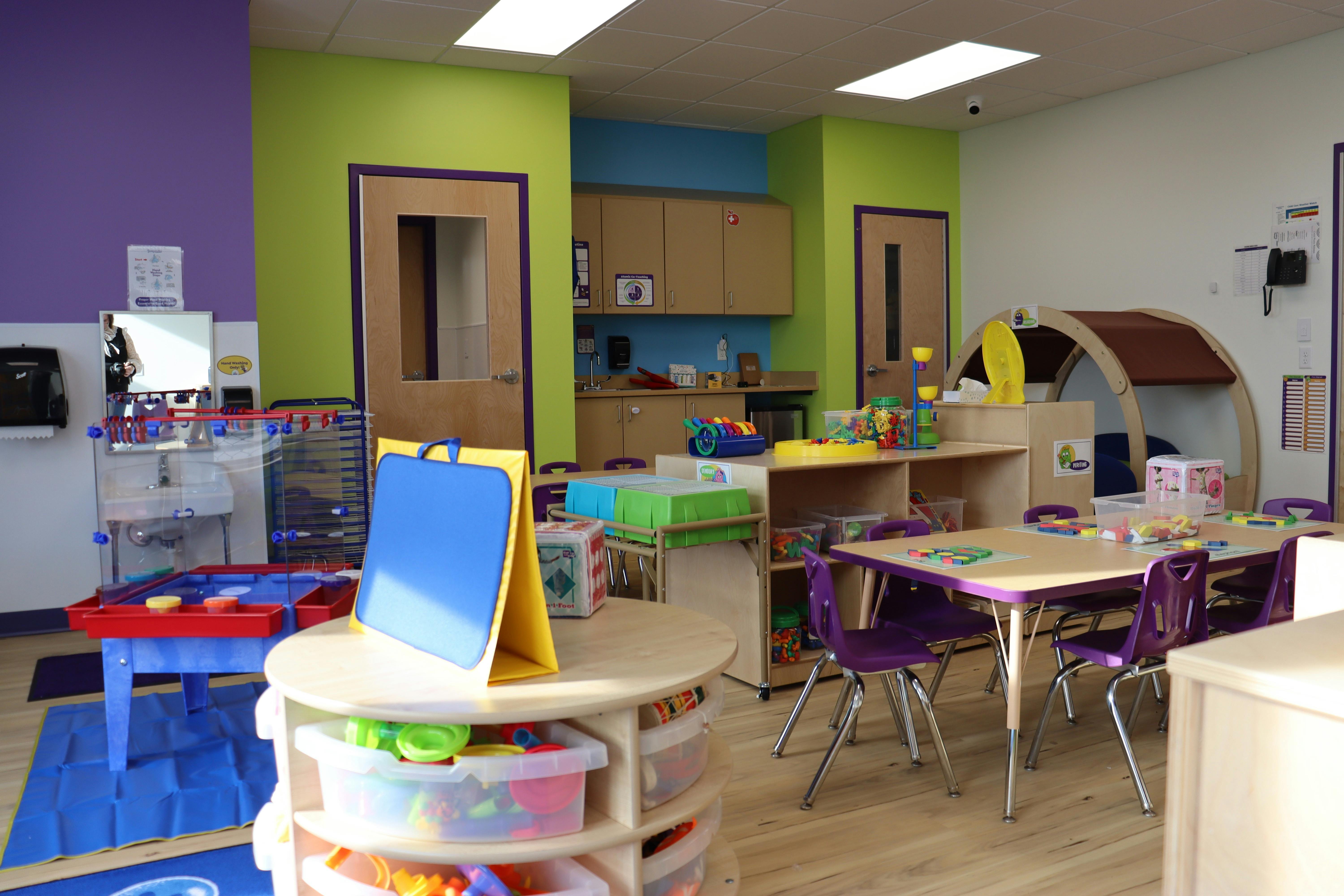 Colorful preschool classroom with various activity stations and child-sized furniture