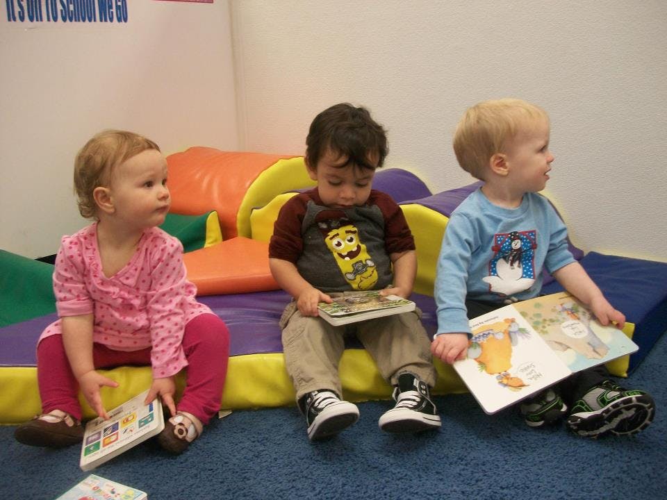 Three children sitting on the floor with books