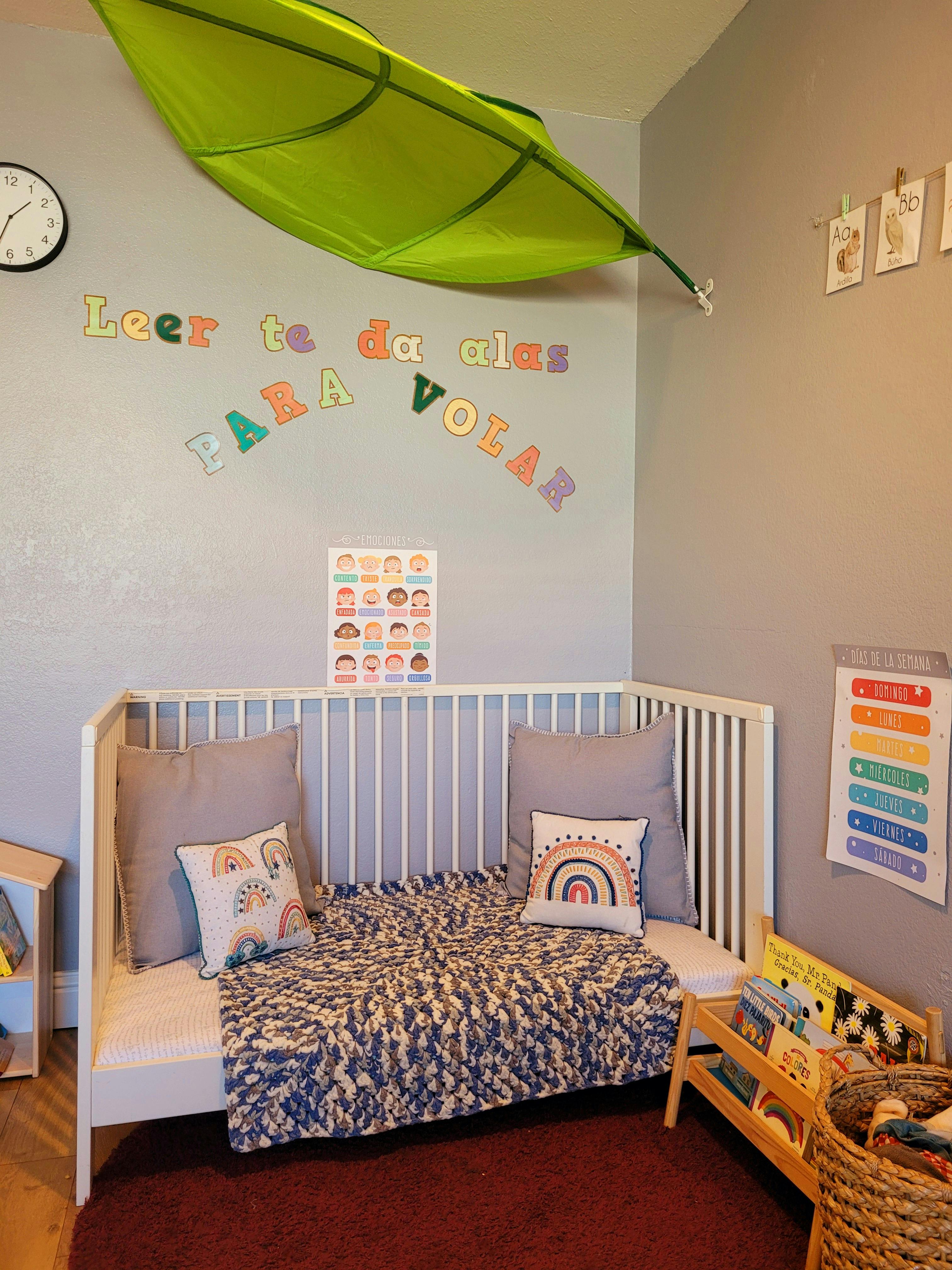 Child's room with a crib, colorful wall letters, and a green canopy
