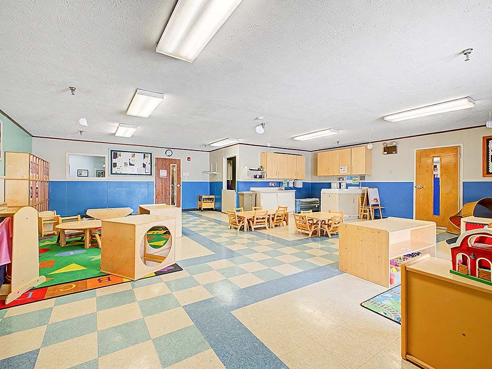 Empty children's classroom with small tables and chairs