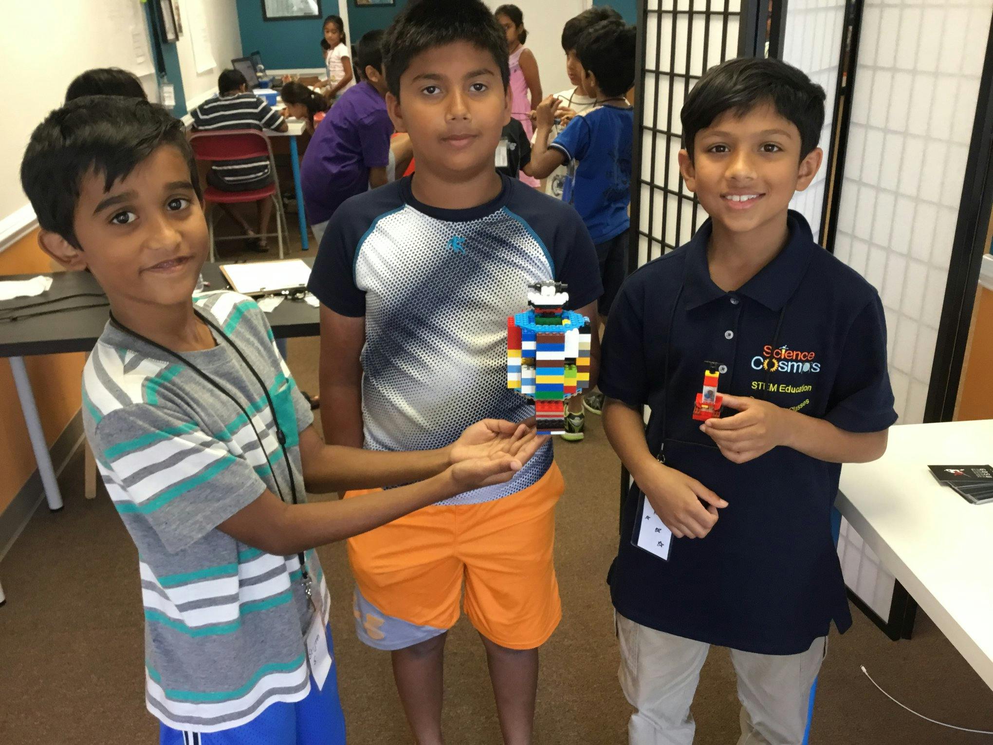 Three children holding Lego creations
