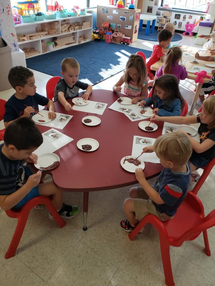 Children sitting at a table doing an art activity in a classroom