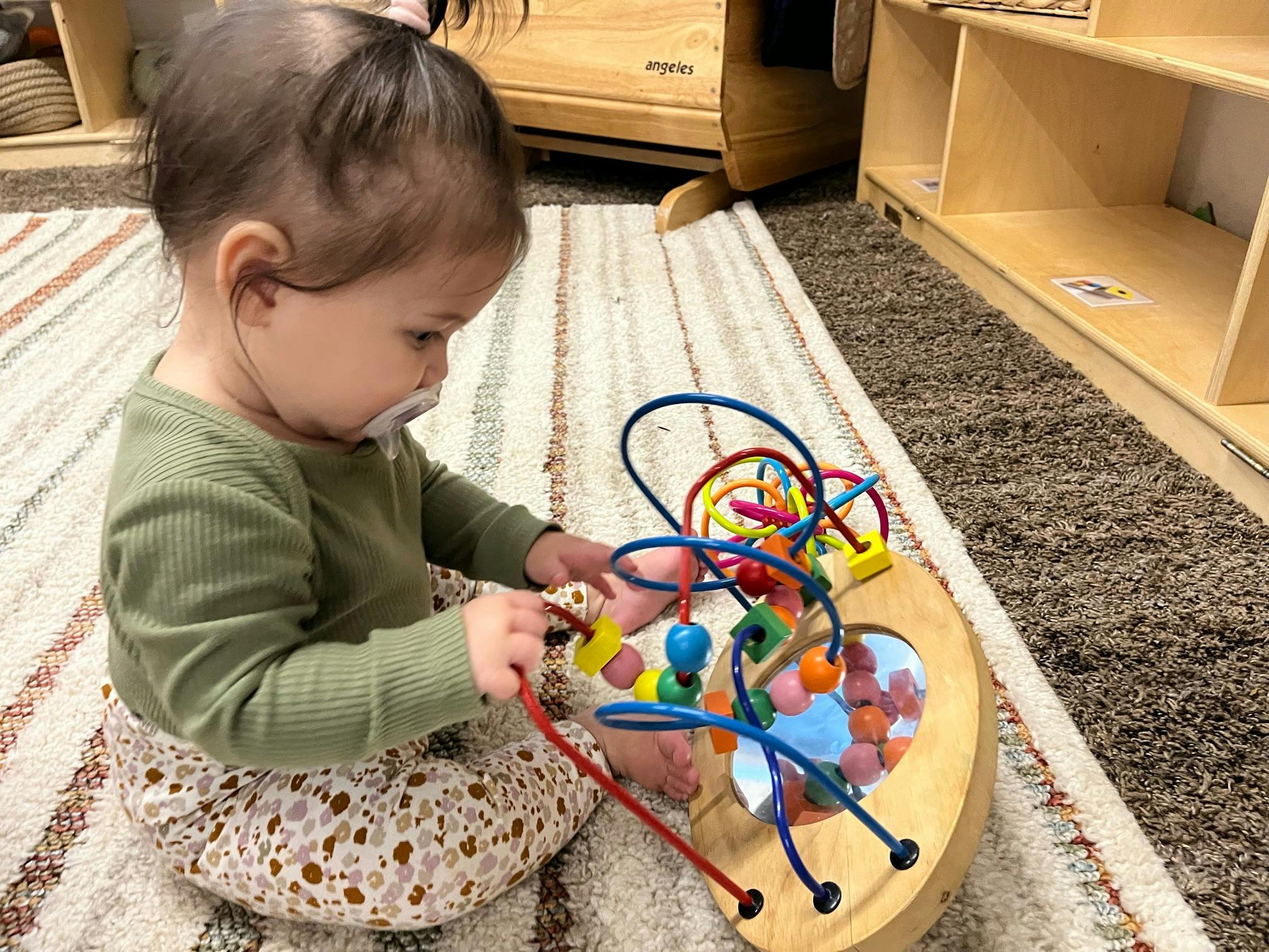 Child playing with a bead maze toy on a rug