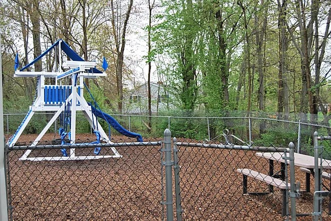 Playground with blue and white playset, slide, and picnic table