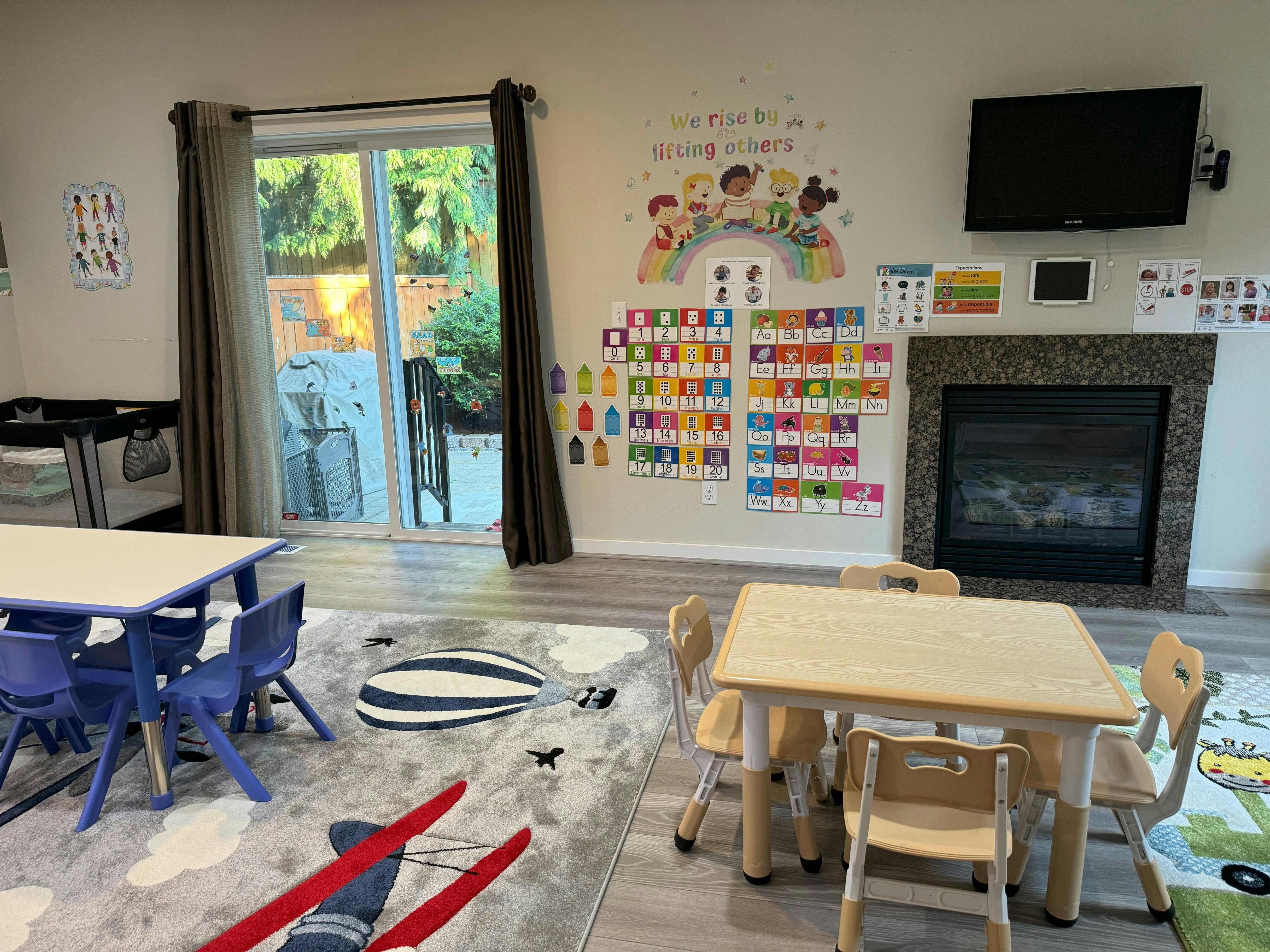 Classroom with small tables and chairs, colorful wall decorations, and a fireplace