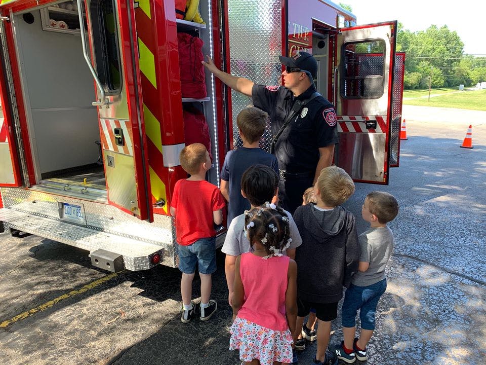 Person in uniform showing children the inside of a fire truck