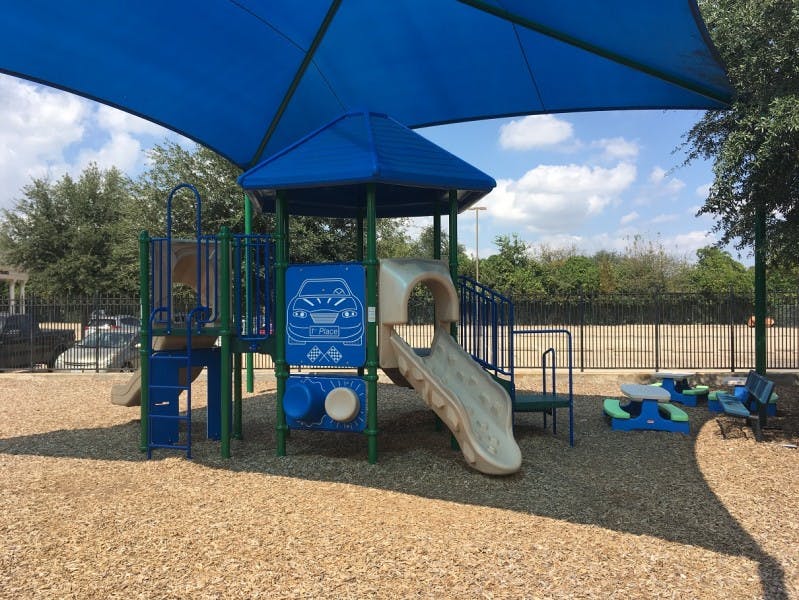 Playground with blue shade canopy, slides, and climbing structures