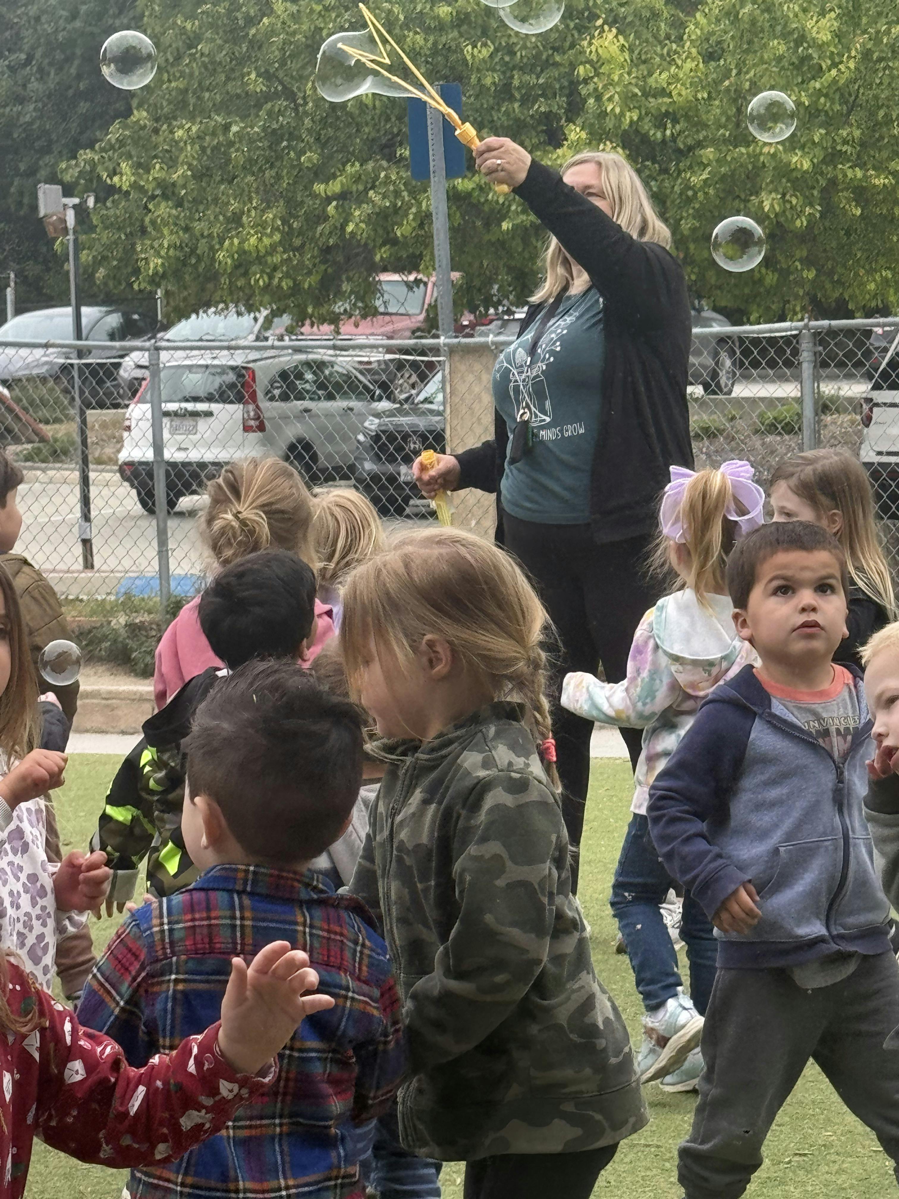 Person blowing bubbles for a group of children outdoors