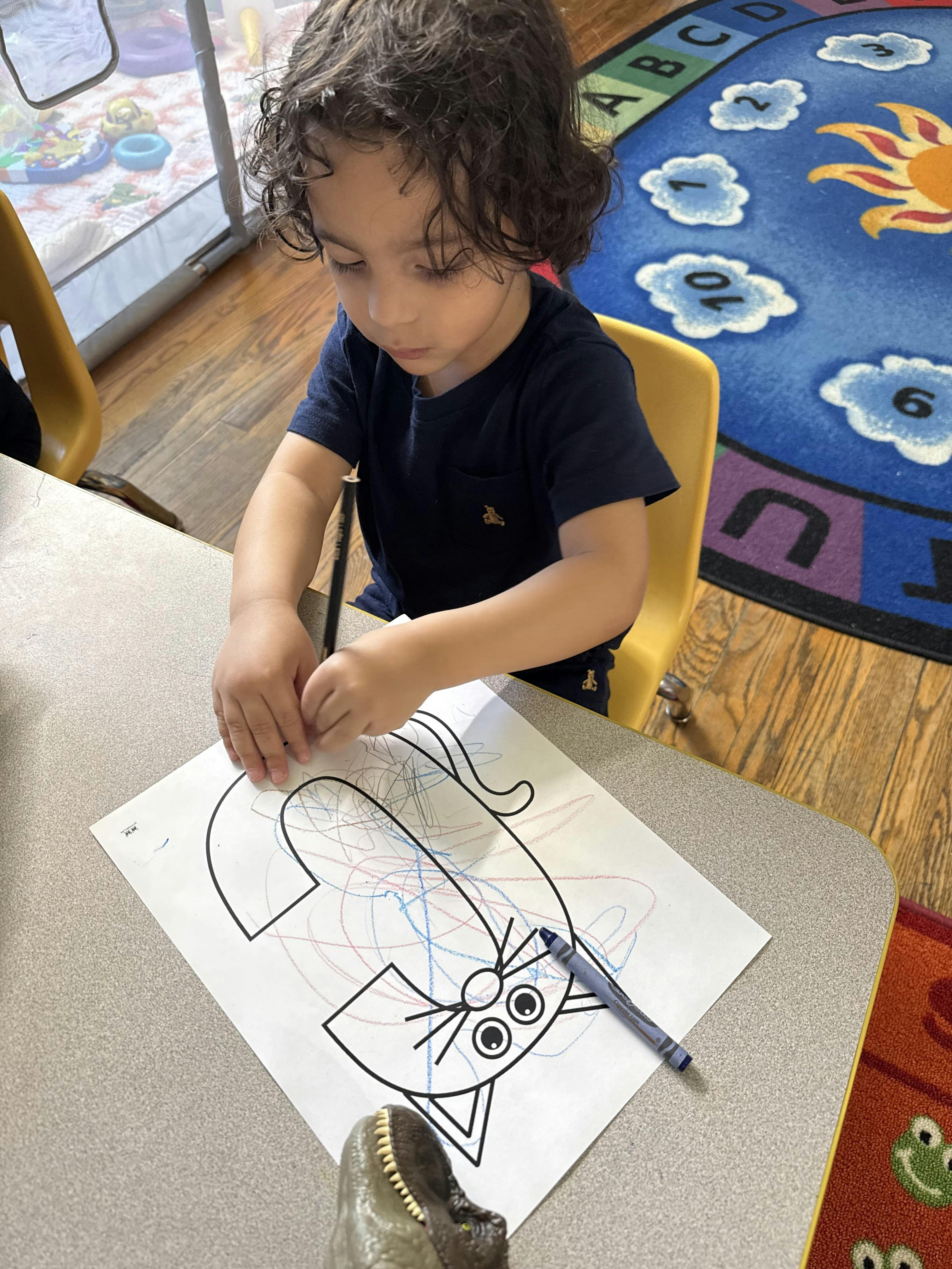 Child coloring a cat shape on a paper at a desk