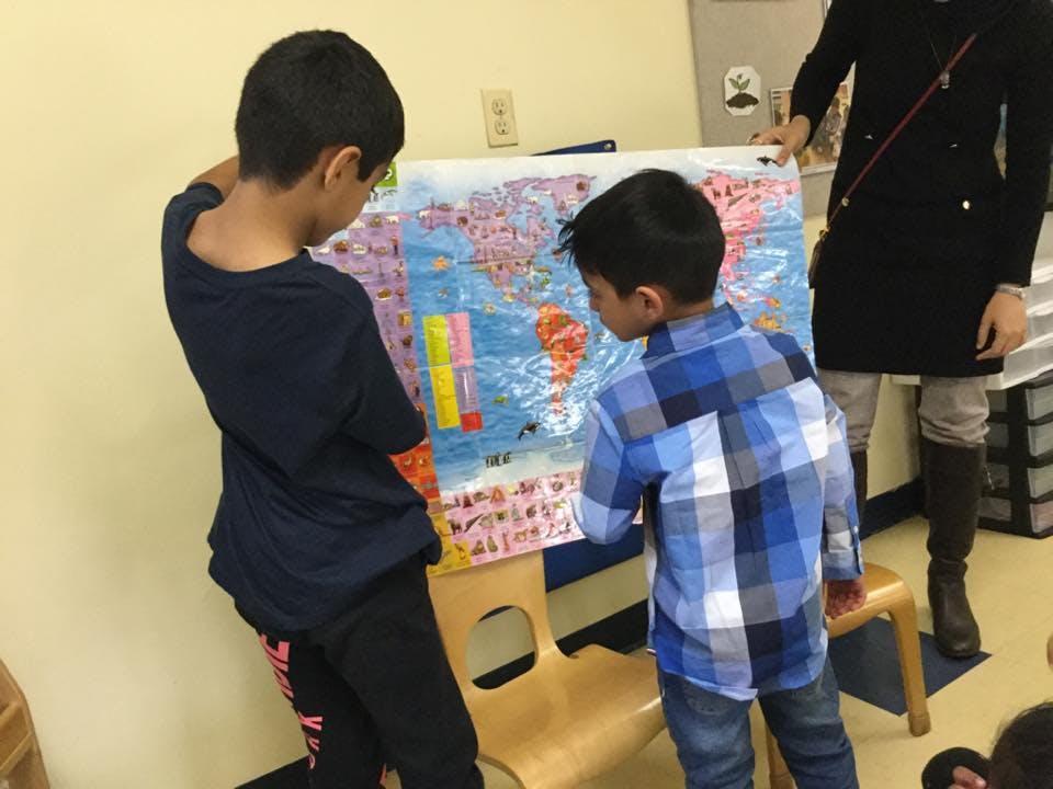 Two children looking at a world map on an easel