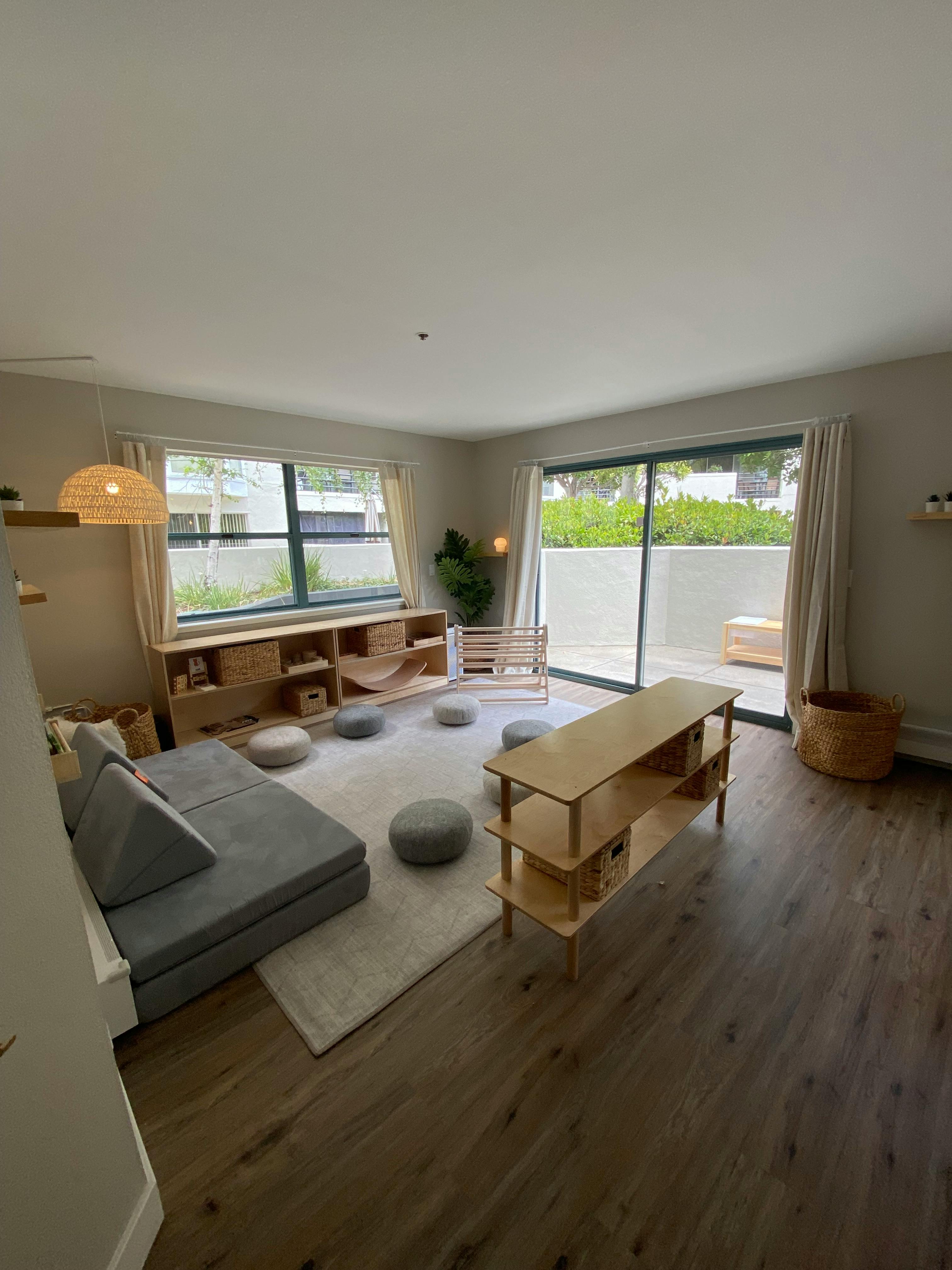 Living room with a gray modular sofa, wooden shelves, and floor cushions