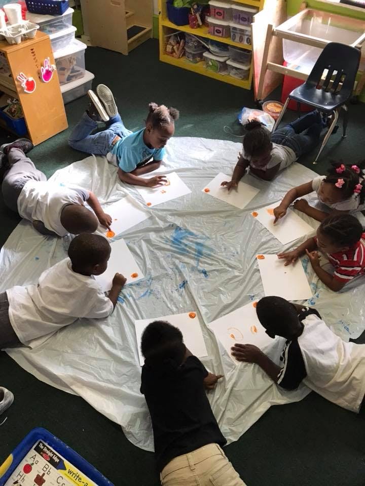Children lying on the floor painting in a classroom