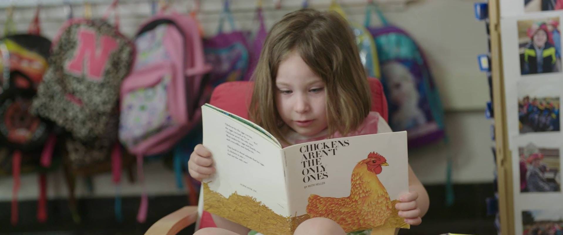 Child reading a book with a chicken on the cover