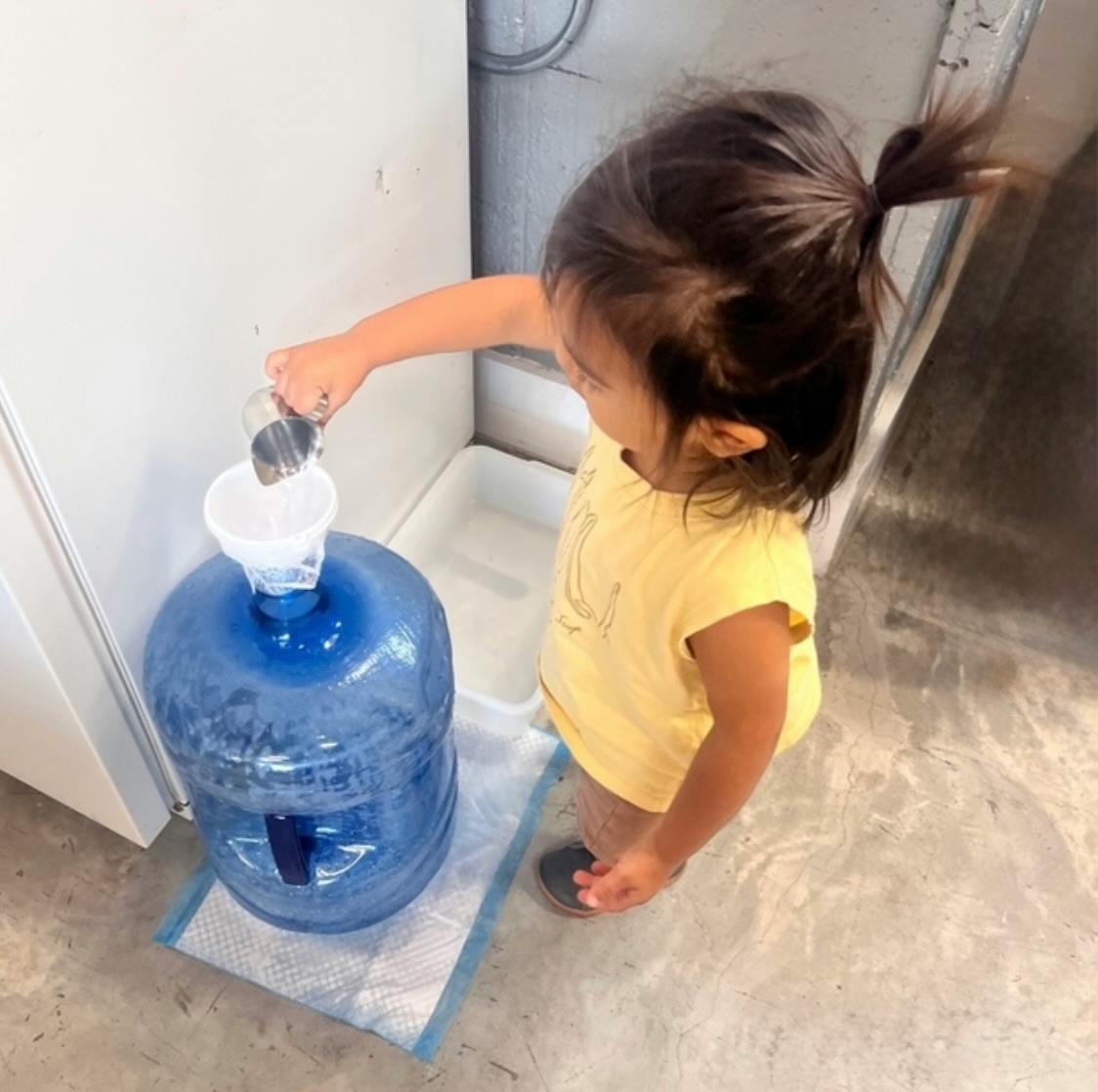 Child pouring water into a large water bottle