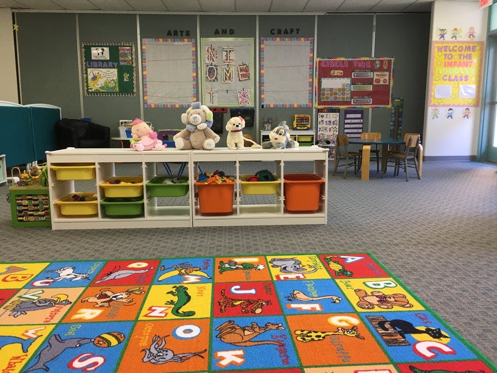 Classroom with a colorful alphabet rug and storage shelves with stuffed animals